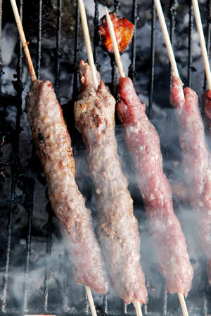 chicken shish kebab on bbq grill in sauce on skewers with tomatoes and peppers