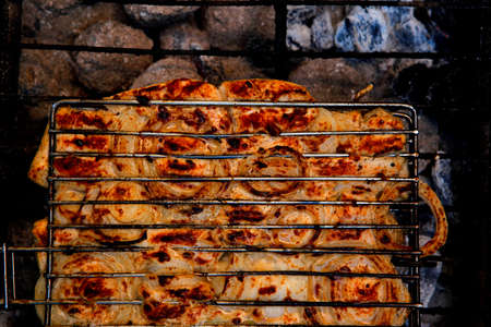 grilling spiced chicken in grid on charcoal bbq with tomatoes and vegetables