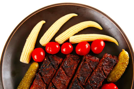 fresh red beef meat served with baby corns and cherry tomatoes on dark plate isolated on white backgroundの写真素材