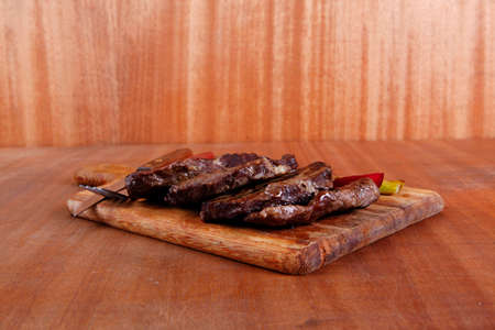 grilled beef pork meat steak fillet with asparagus  hot red peppers and cutlery on wooden cutting...
