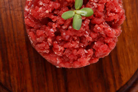 very big raw hamburger cutlet with sprouts and chilli pepper on wooden plate isolated over white の写真素材