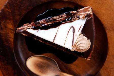 sweet brownie chocolate cream cake topped with white chocolate and cream with chocolate with chocolate sauce on wooden の写真素材