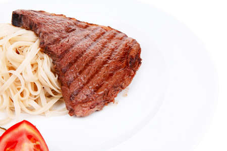 italian food : pasta with tomato on basil and roasted sirloin beef  steak on plate isolated over white backgroundの写真素材