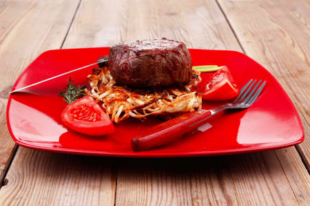 grilled beef fillet pieces on noodles , red hot chili pepper with tomato on red plate over wood tableの写真素材