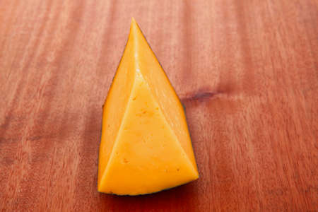 chunk of aged french gruyere or cheddar cheese in black shell on wooden tableの写真素材