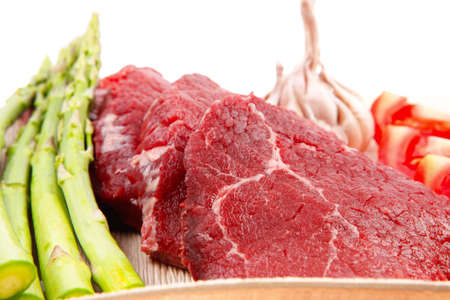 fresh raw beef meat steak fillet on wooden plate with asparagus and tomatoes ready to prepare...