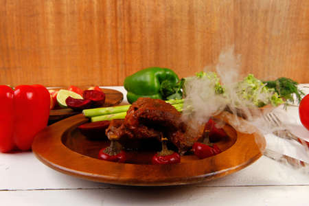 grilled roast red beef meat served on wooden dishes with peppers cutlery salad and vegetables on white wooden tableの写真素材