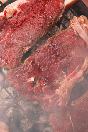 fresh raw beef meat fillet mignon on black grill grid over charcoal on brazierの写真素材