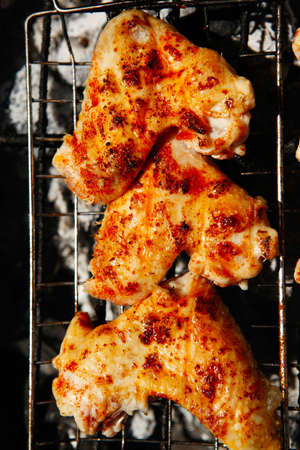 bbq grill meat - ready chicken wings on grid over charcoalの写真素材