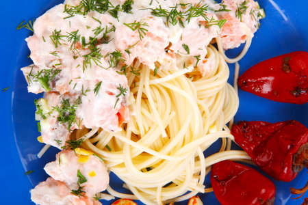 fresh rose wild salmon baked in cream cheese sauce with italian pasta and red hot pepper on blue plate isolated over white backgroundの写真素材