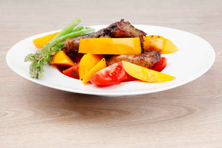 meat food : grilled red beef fillet with mango tomatoes and asparagus , served on white dish over wooden tableの写真素材