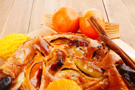 baked food : big apple pie served with fresh apples, raw lemon and mandarin,  tea cup on wooden plate over tableの写真素材