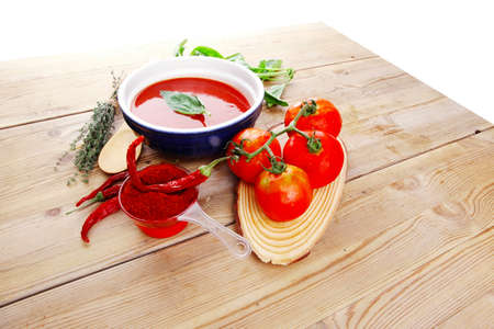 hot fresh diet tomato soup with basil thyme and dry pepper in big bowl on wood tableの写真素材
