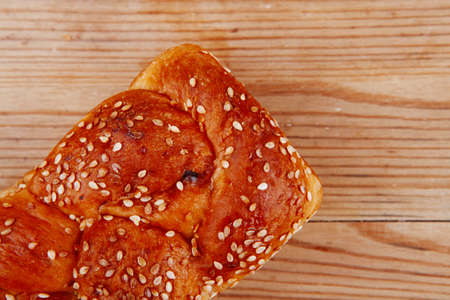 fresh loaf of light wheat bread topped by sesame seeds over wooden tableの写真素材