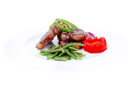 roasted beef meat strips steak on white ceramic plate with sweet pea and tomatoes isolated over white backgroundの写真素材