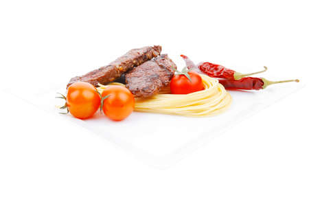 grilled beef fillet with pasta and tomatoes on white plate isolated over white の写真素材