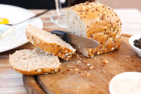wooman cut the home made bread on wooden board near tapases outside cafe