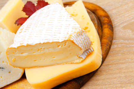 edam parmesan and brie cheese on wooden platter over wooden table