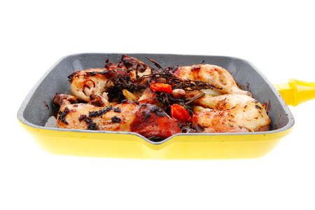 grilled chicken legs with tomatoes and thyme cooked on yellow ceramic pan isolated on white backgroundの写真素材