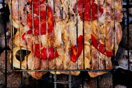 grilling spiced chicken in grid on charcoal bbq with tomatoes and vegetablesの写真素材