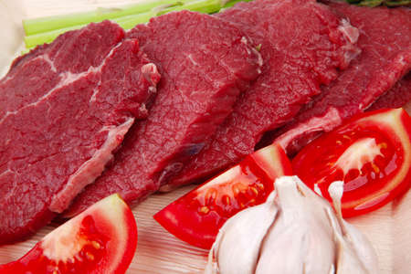 fresh raw beef meat steak fillet on wooden plate with asparagus and tomatoes ready to prepare...