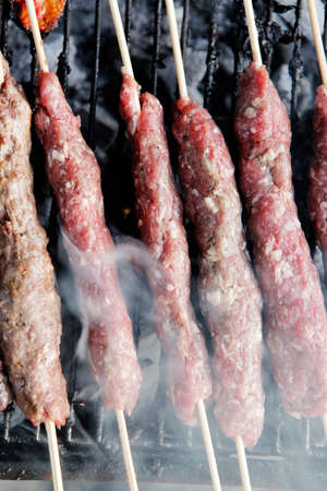 chicken shish kebab on bbq grill in sauce on skewers with tomatoes and peppersの写真素材