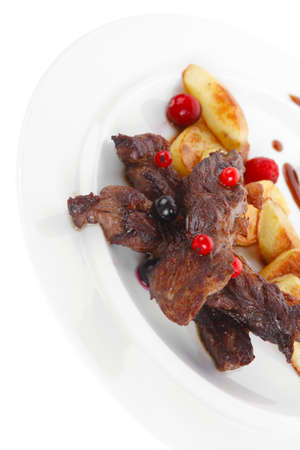 grilled beef meat with berries fried potatoes and cherry under sweet honey sauce on white plate isolated over white backgroundの写真素材