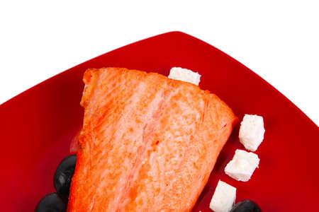 roast salmon fish meat fillet with lemon black greek olives white goat cheese on red plate isolated over white backgroundの写真素材