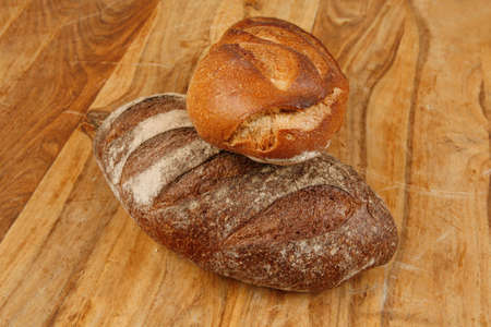 different rye and white flour french bread loaf with on light wooden table background