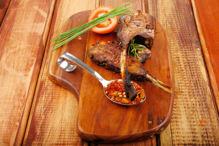 savory plate on wood : grilled ribs on plate with chives and tomato isolated on wooden tableの写真素材