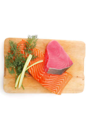uncooked fresh salmon and red tuna fish pieces served over wooden board isolated on white backgroundの写真素材