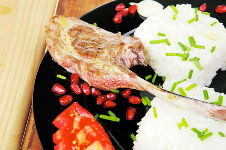 meat savory: roast veal ribs with rice garnish and pomegranate seeds on black over woodの写真素材