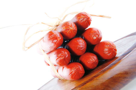 smoked sausages served on a wooden plate over whiteの写真素材