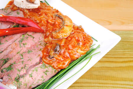 hot beef on plate over wooden tableの写真素材