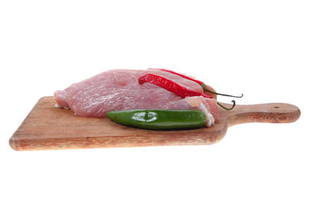 fresh raw turkey meat pieces on wooden cutting plate with red and green hot chili pepper isolated over white backgroundの写真素材