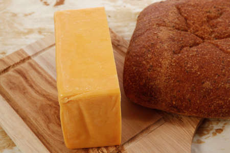 aged italian cheddar cheese on wooden board with rye ciabatta on used baking paper as backgroundの写真素材