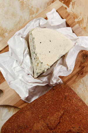 aged italian deli fresh blue stilton cheese and rye ciabatta served on wooden cutting plate on used...