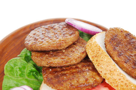 several large roast hamburger with loaf on wooden plate isolated over white backgroundの写真素材