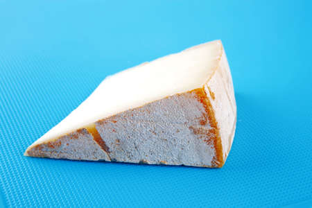 piece of light swiss cheese on blue boardの写真素材