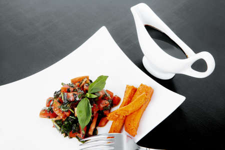 vegetable salad : cherry tomatoes and basil with sweet baked potato served on white plate with sauceboat full blask soy sauce on woodの写真素材