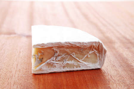 fresh aged french gouda cheese on wooden tableの写真素材