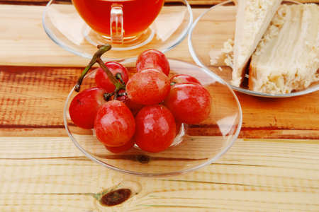 grapes with tea and cake on wooden tableの写真素材
