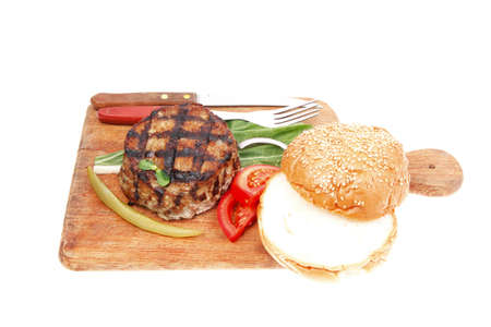 extra thick hot beef meat hamburger lunch on wooden plate with tomatoes and salad isolated on white backgroundの写真素材