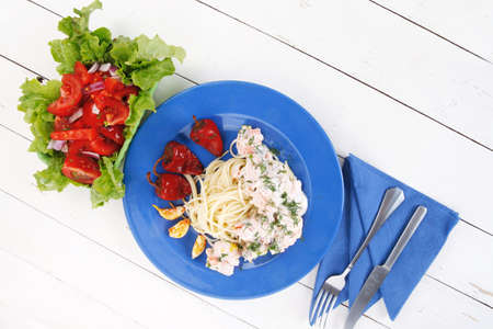 fresh rose wild salmon baked in cream cheese sauce with italian pasta and red hot pepper on blue plate over white wooden table with vegetable saladの写真素材