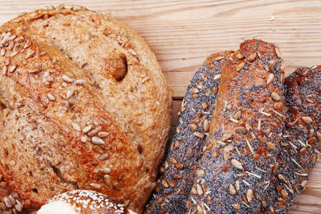 hot rural french round rye bread and baguette topped with sunflower seeds and sweet bagels on wooden...