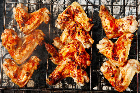 bbq grill meat - ready chicken wings on grid over charcoal