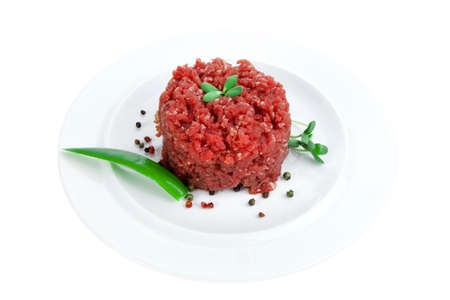 very big raw hamburger cutlet with sprouts and chilli pepper on white plate isolated over white backgroundの写真素材