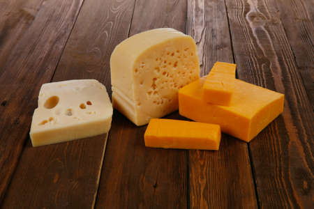 various types of fresh raw aged delicatessen cheese on wooden table cheddar edam swissの写真素材