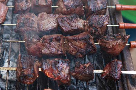fresh raw beef fillet steak red meat brisket on skewers barbecue brazier grid full burned charcoalの写真素材