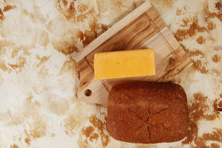 aged italian cheddar cheese on wooden board with rye ciabatta on used baking paper as backgroundの写真素材